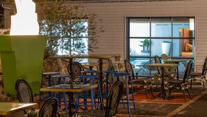 An outdoor seating area with tables and chairs, a large white sculpture, and a view of the interior through a window. - Le M Hôtel & Spa Honfleur (Honfleur)