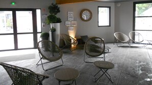 A lobby with wicker chairs, a clock, and a potted plant. - Le M Hôtel & Spa Honfleur (Honfleur)