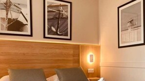 A hotel room with a neatly made bed, two pillows, a headboard, and three framed pictures on the wall. - Le M Hôtel & Spa Honfleur (Honfleur)