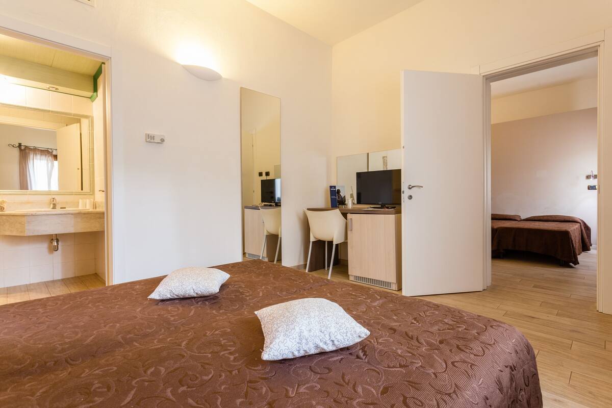 A hotel room with a bed, a desk, a chair, and a TV.