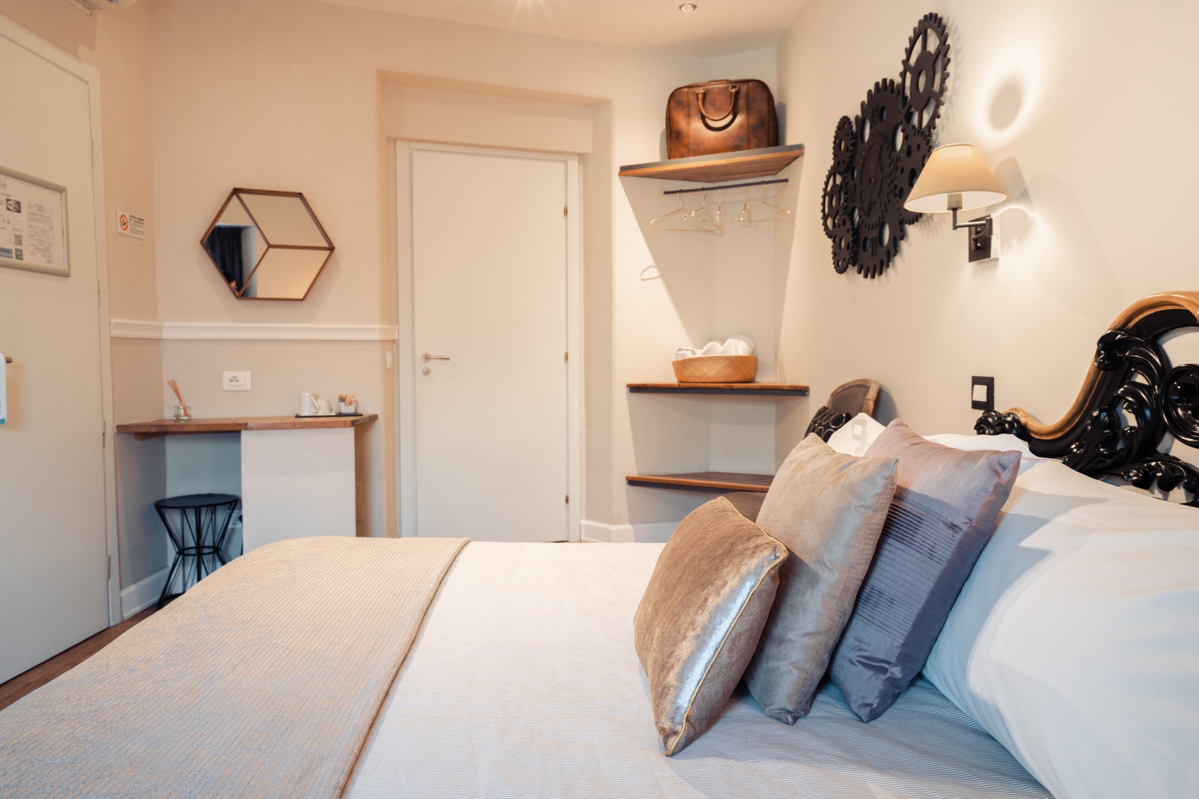 Un dormitorio con cama, mesitas de noche, armario, espejo y una lámpara de pared.