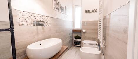 A modern bathroom with a large oval sink, a toilet, and a mirror.