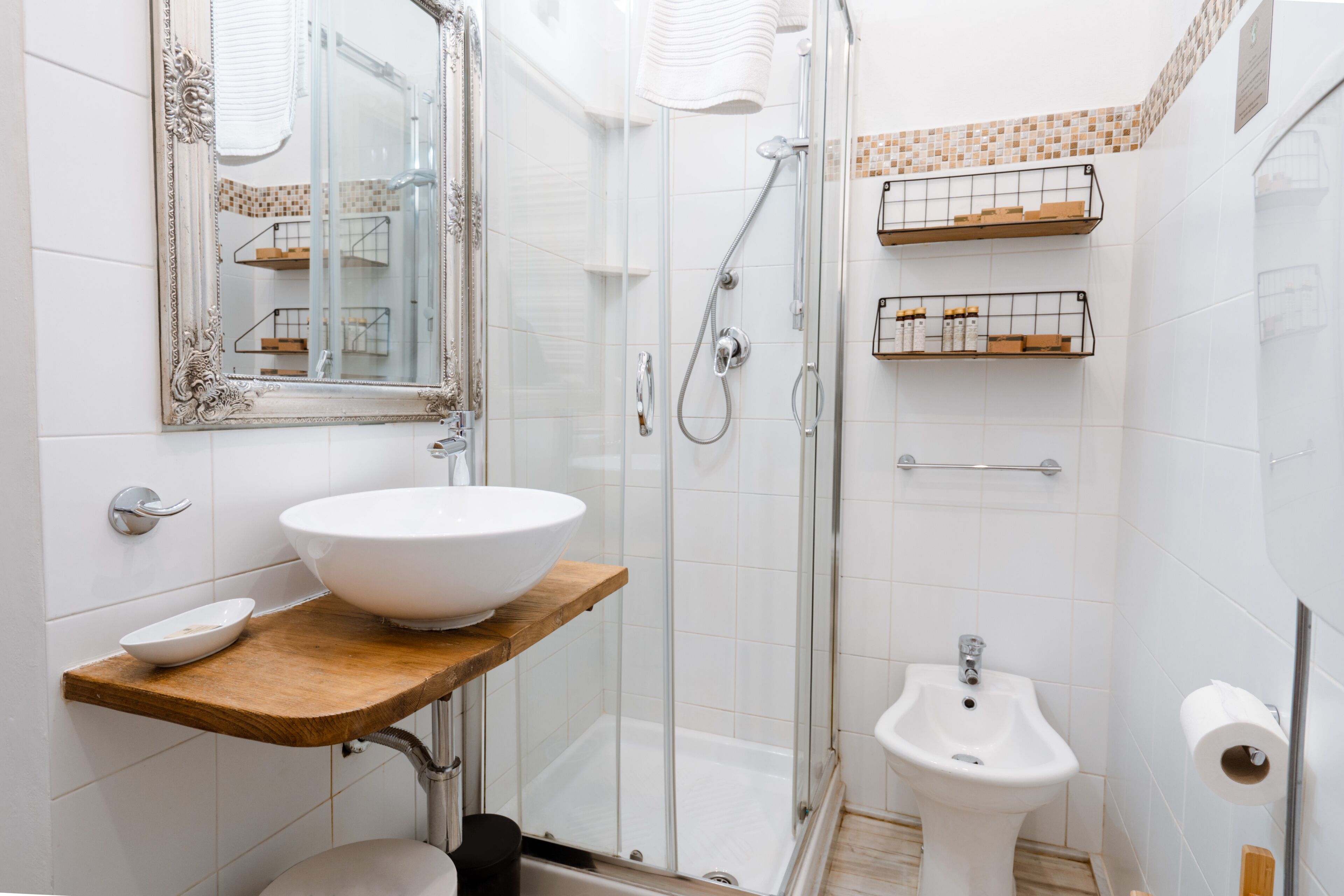Un baño moderno con un lavamanos grande de color blanco, una ducha con cerramiento de vidrio y un bidé.