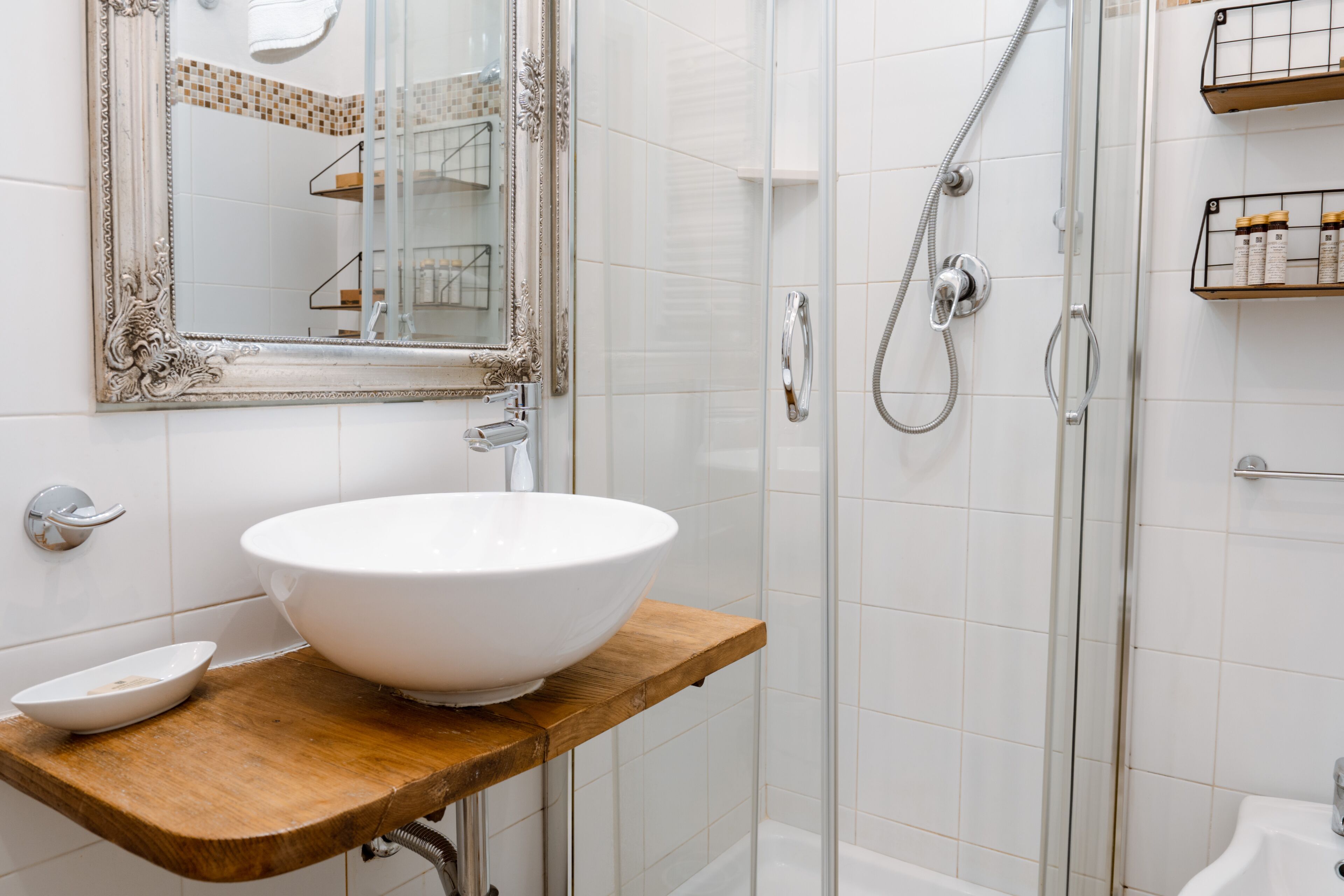 A bathroom with a white sink, a wooden countertop, a large mirror, and a glass shower enclosure.