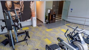 A gym with exercise equipment, a water dispenser, and a trash bin.
