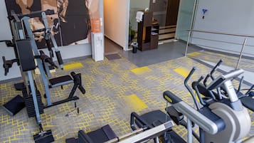 A gym with exercise equipment, a water dispenser, and a trash bin.
