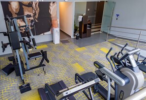 A gym with exercise equipment, a water dispenser, and a trash bin.