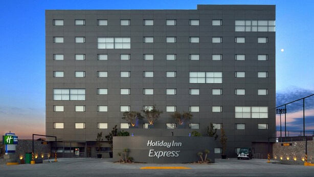 A Holiday Inn Express building with a modern facade, multiple windows, and a sign indicating the entrance.