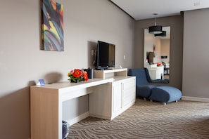 A modern hotel room with a flat-screen TV, a white console table, a blue sofa, and a patterned carpet. - Holiday Inn Express Pachuca by IHG (Pachuca)
