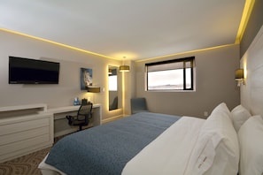 A hotel room with a bed, desk, chair, TV, and a window with a city view. - Holiday Inn Express Pachuca by IHG (Pachuca)