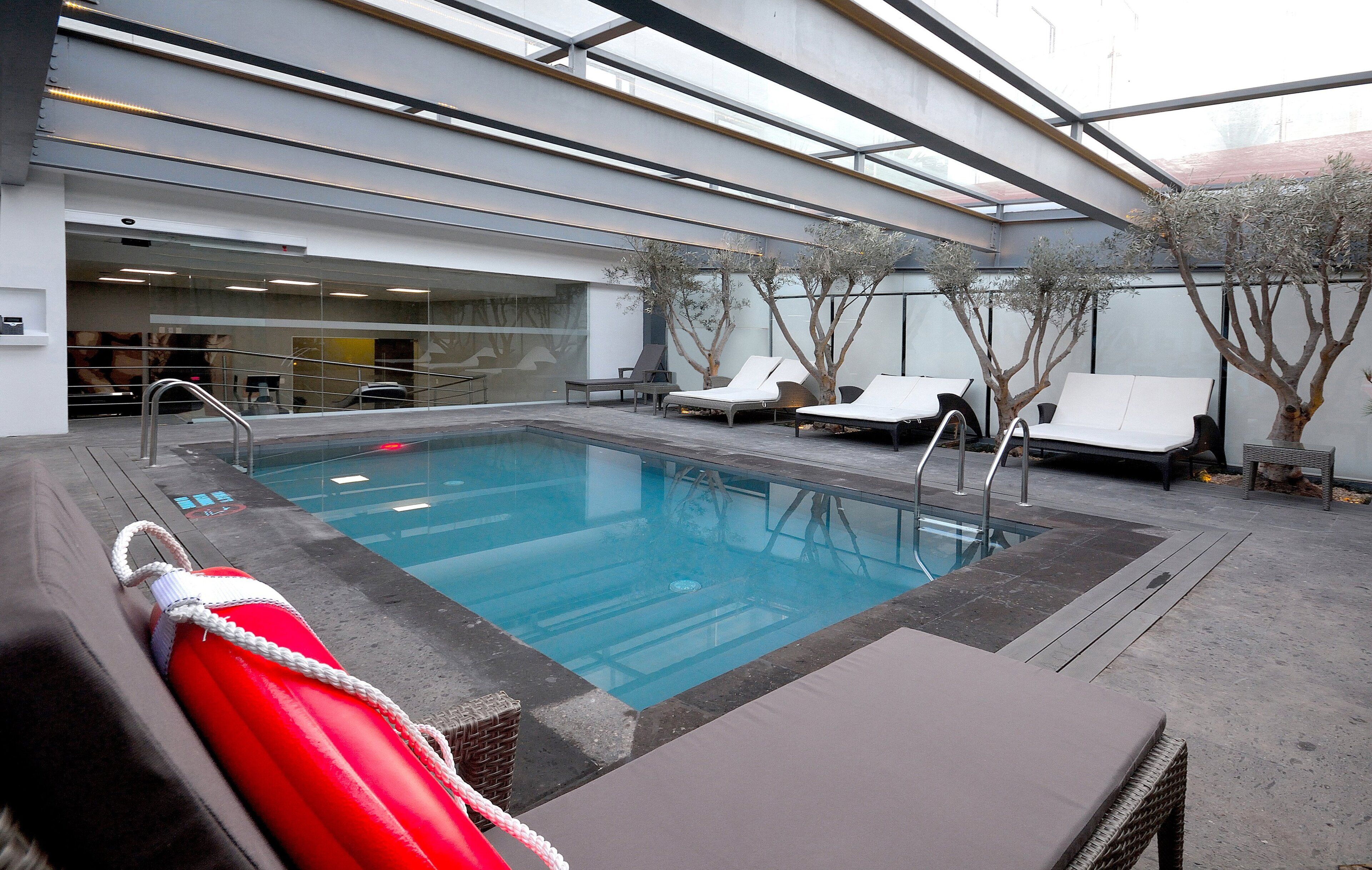 Una piscina interior con sillones de descanso y una silla para salvavidas.