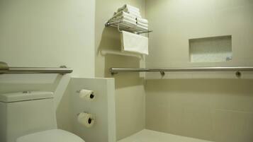 Un baño con inodoro, secamanos y un perchero con toallas dobladas.