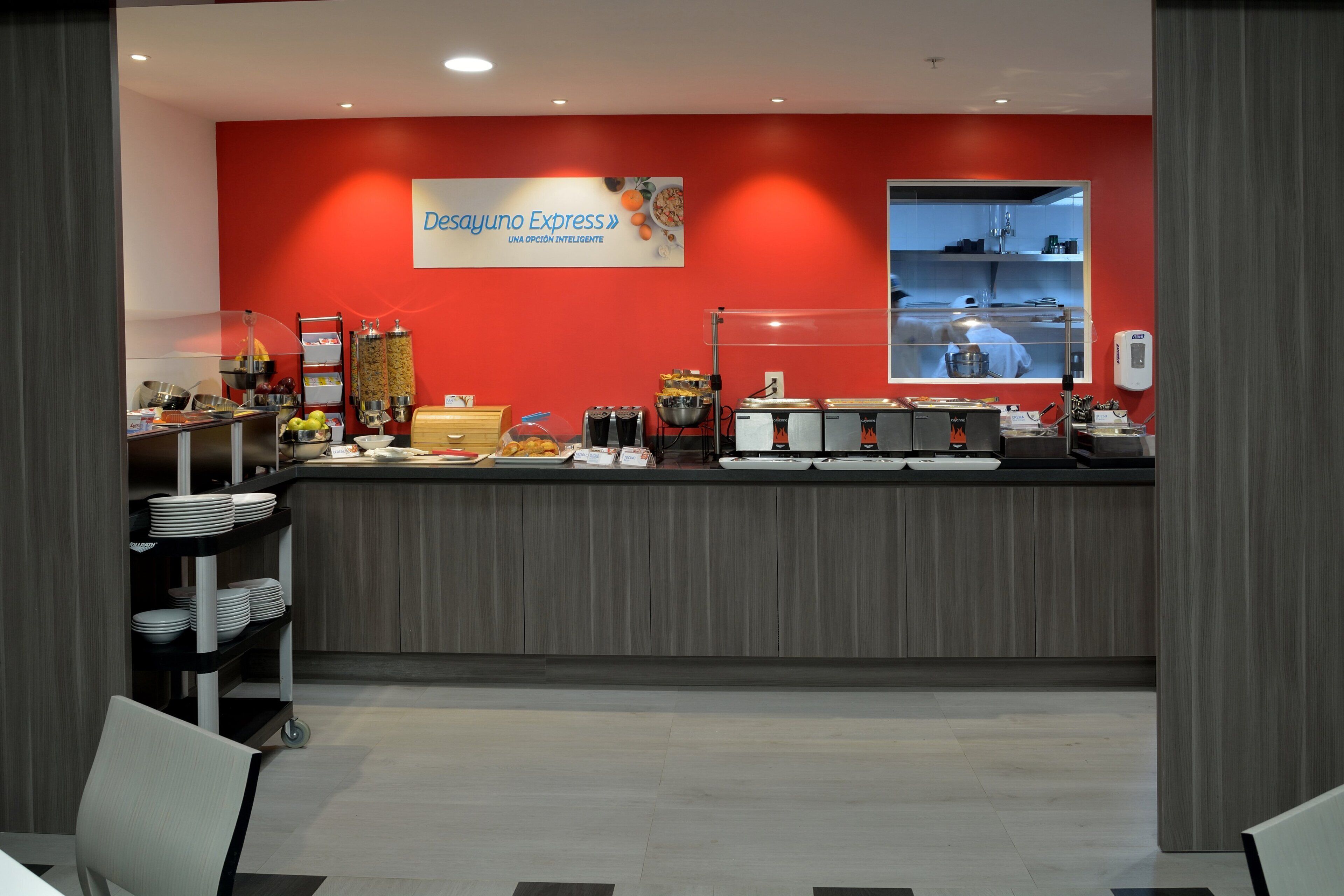 A breakfast bar with a red wall, a window, and various food items.