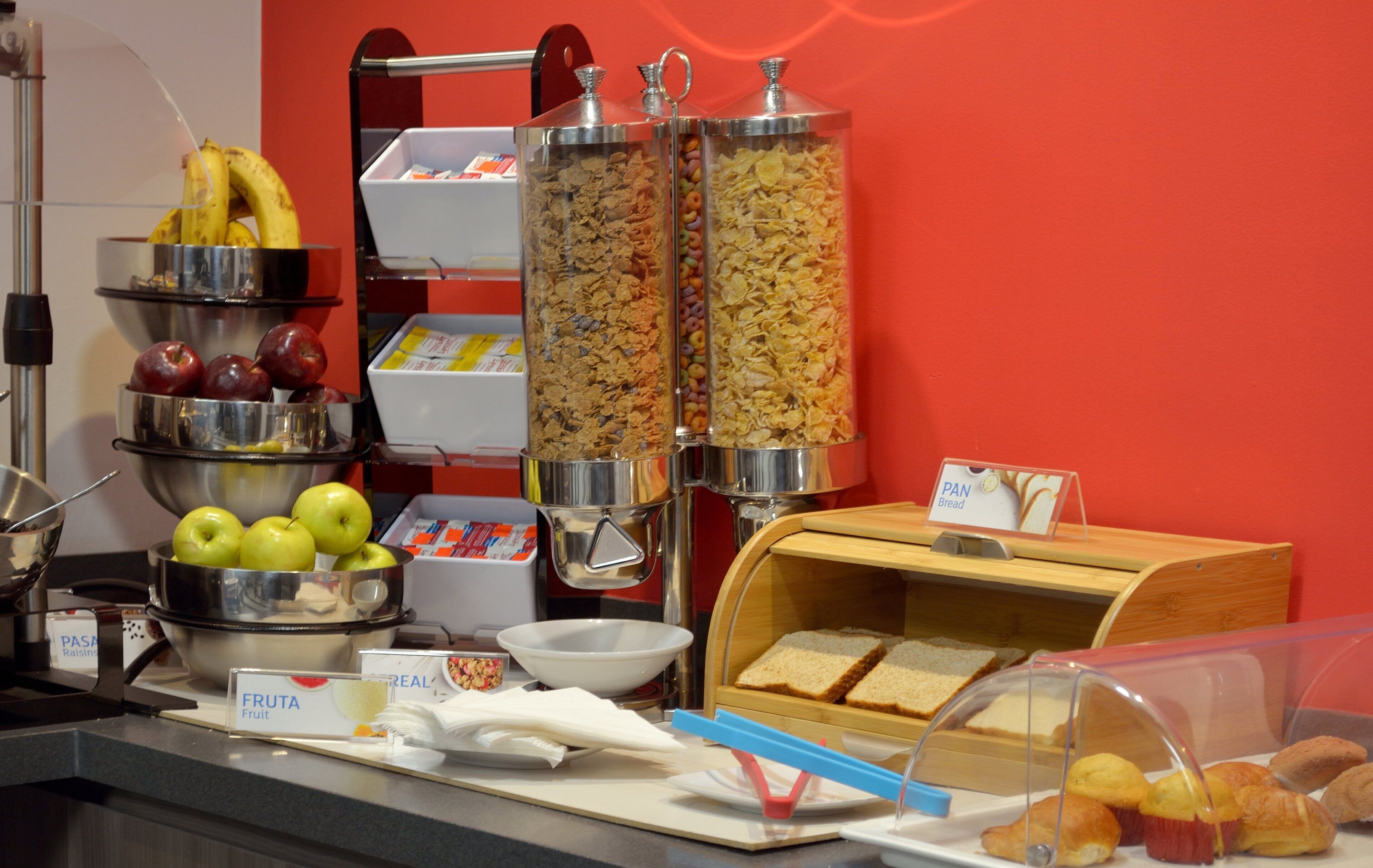 Un bufé de desayuno con diversas opciones de comida, incluyendo frutas, cereales y pan.