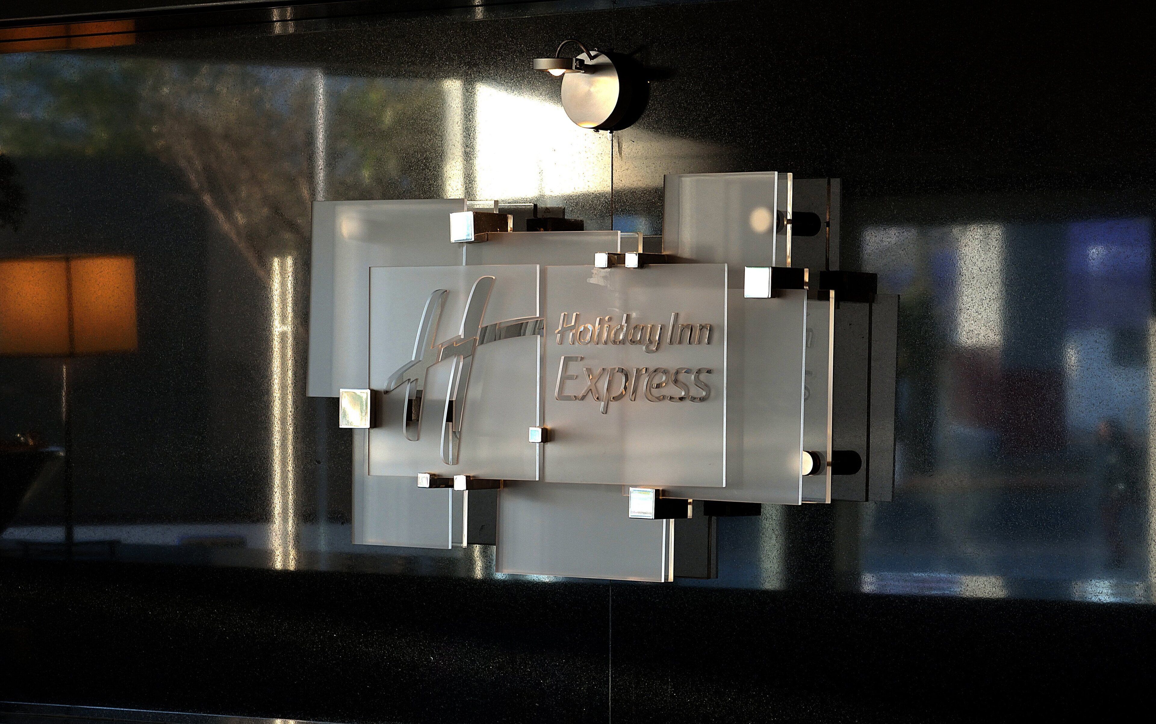 A metallic sign with the inscription 'Holiday Inn Express' on a reflective surface.