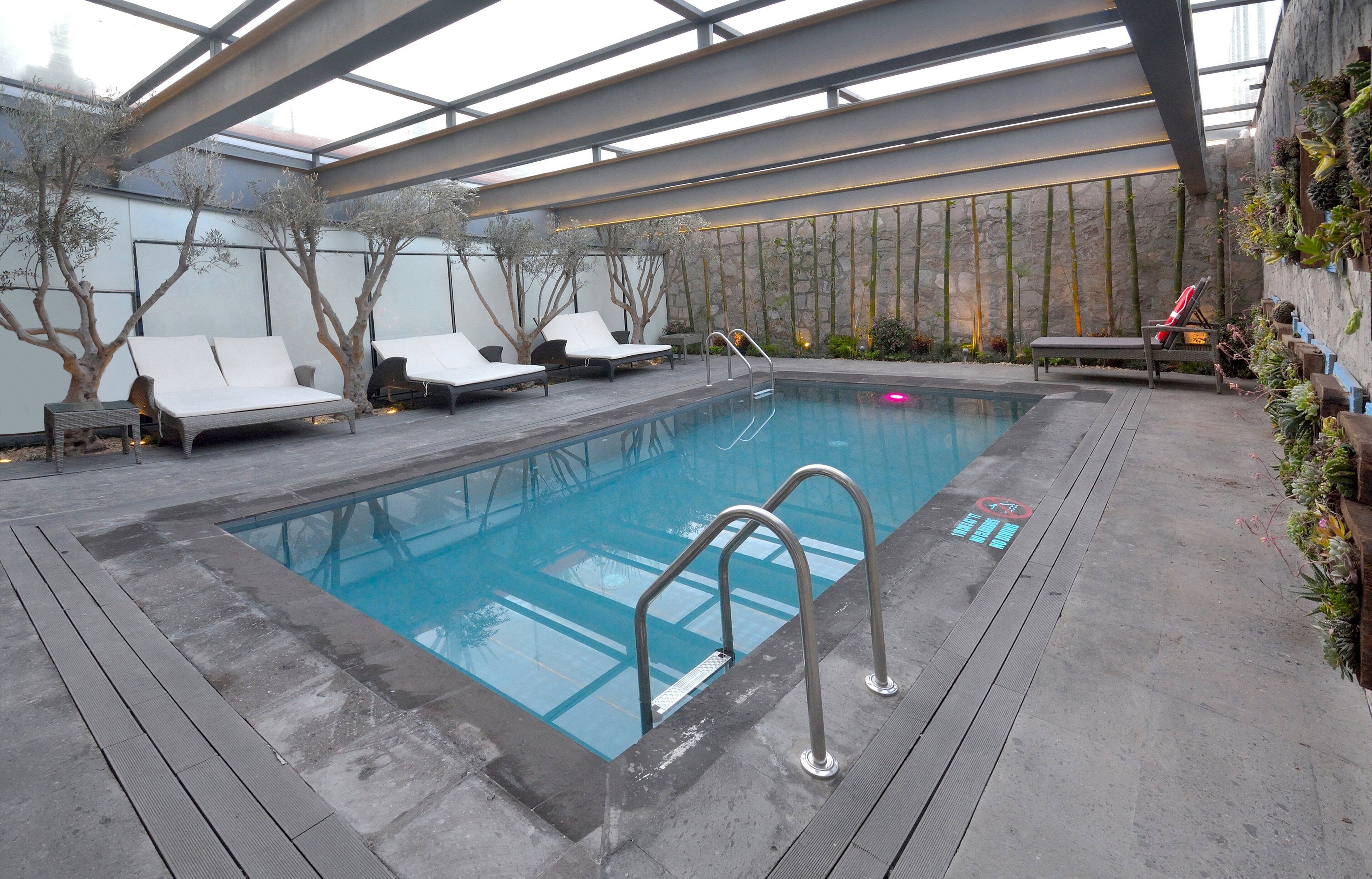 An indoor swimming pool with lounge chairs and a stone wall.