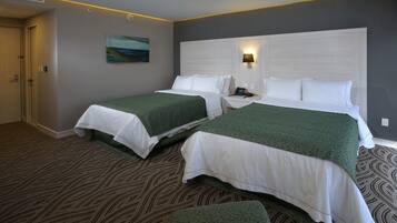 A hotel room with two beds, a painting on the wall, and a patterned carpet.