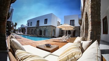 Una piscina al aire libre, sombrillas, sillones reclinables de piscina