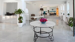 A spacious, well-lit interior with a central chandelier, a round table with a floral centerpiece, and a dining area in the background. - Saraya Bodrum Hotel (Bodrum)