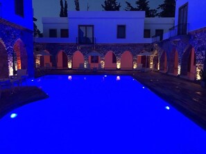 A swimming pool with a stone wall and arches, surrounded by lounge chairs and umbrellas. - Saraya Bodrum Hotel (Bodrum)