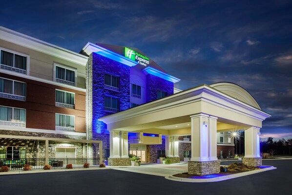 A Holiday Inn Express & Suites hotel with a covered outdoor area and a brick facade.