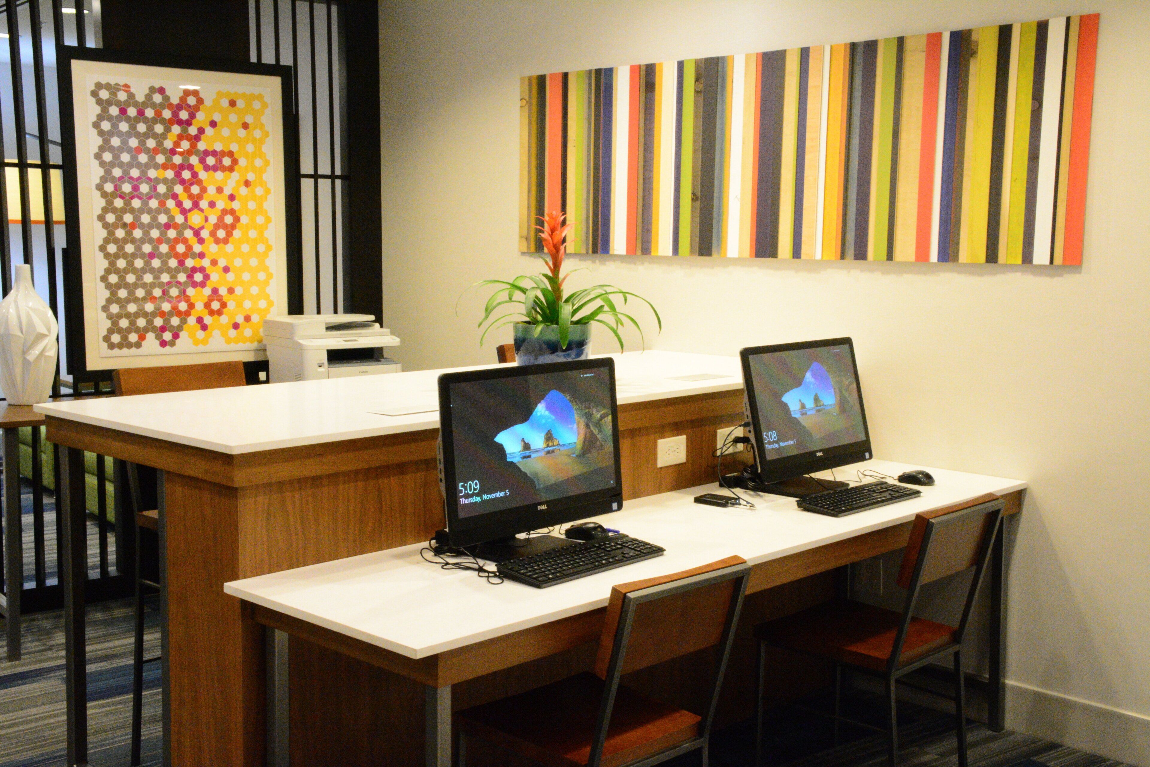 A reception area with two computer workstations, a printer, and a decorative wall piece.