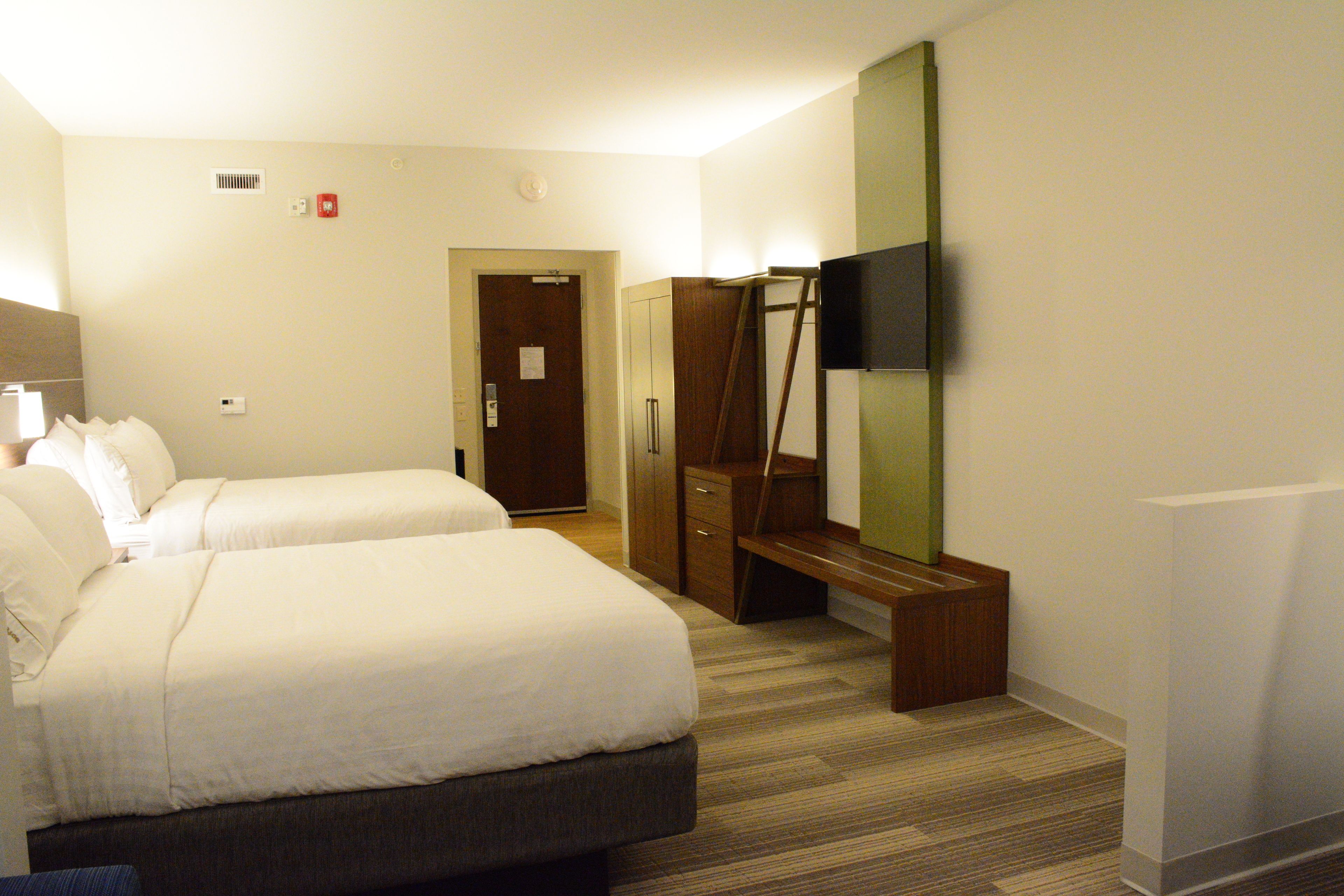 Quarto de hotel com duas camas, um guarda-roupa, um espelho e uma televisão.