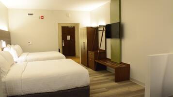 A hotel room with two beds, a wardrobe, a mirror, and a TV.