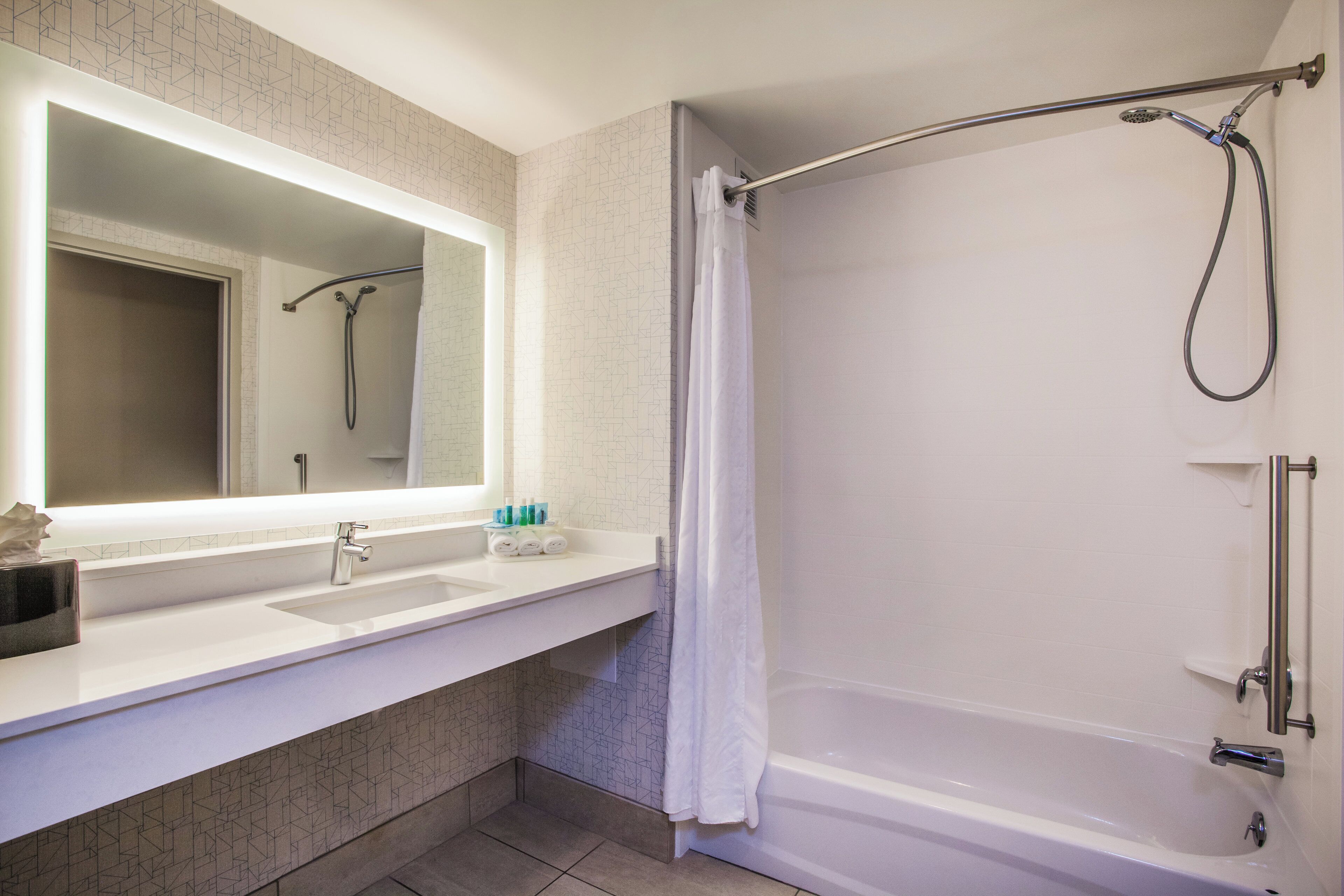 A bathroom with a shower, a sink, and a mirror.