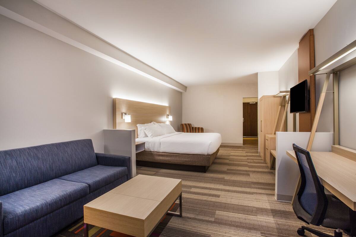 Una habitación de hotel con cama, sofá, escritorio y televisión.