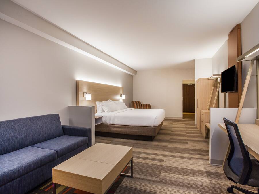 A hotel room with a bed, a sofa, a desk, and a TV.