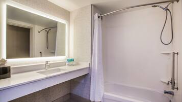A modern bathroom with a white sink, mirror, and bathtub.