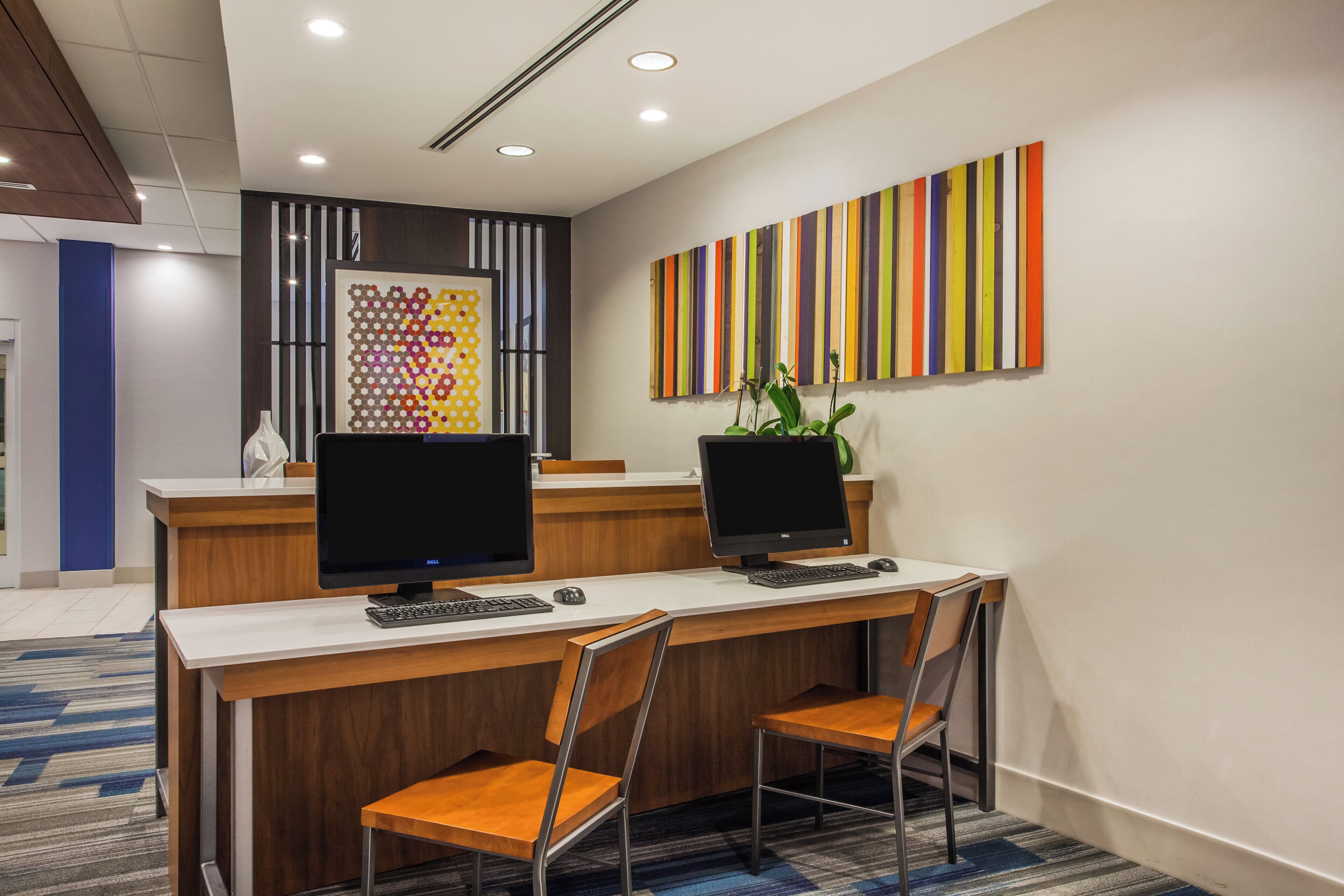 A reception area with two desks, chairs, and a colorful striped wall art piece.