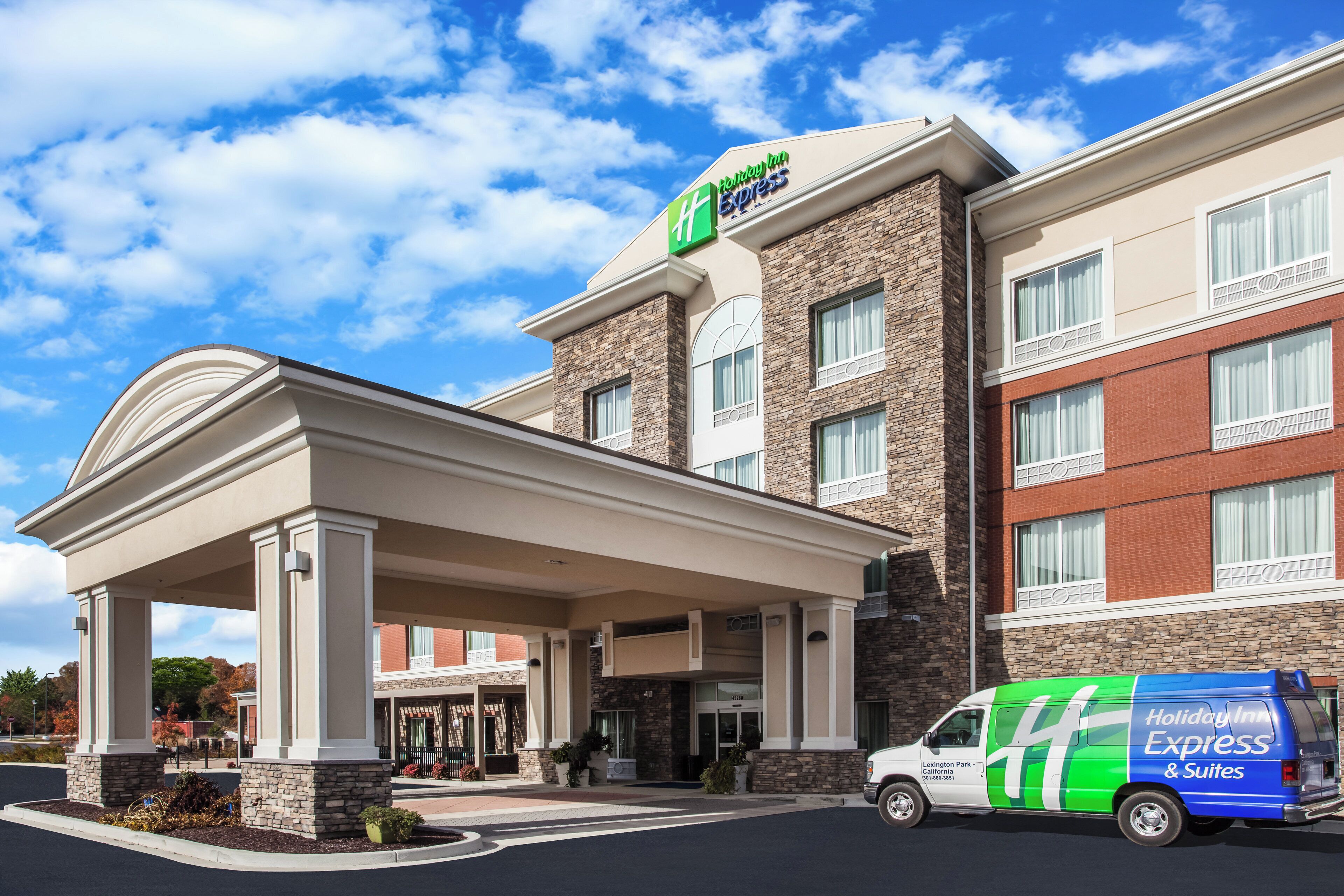 Een Holiday Inn Express gebouw met een overdekte ingang, een gevel van natuursteen en een bestelwagen ervoor geparkeerd.