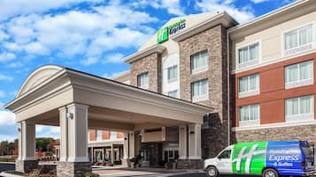 Een Holiday Inn Express gebouw met een overdekte ingang, een gevel van natuursteen en een bestelwagen ervoor geparkeerd.