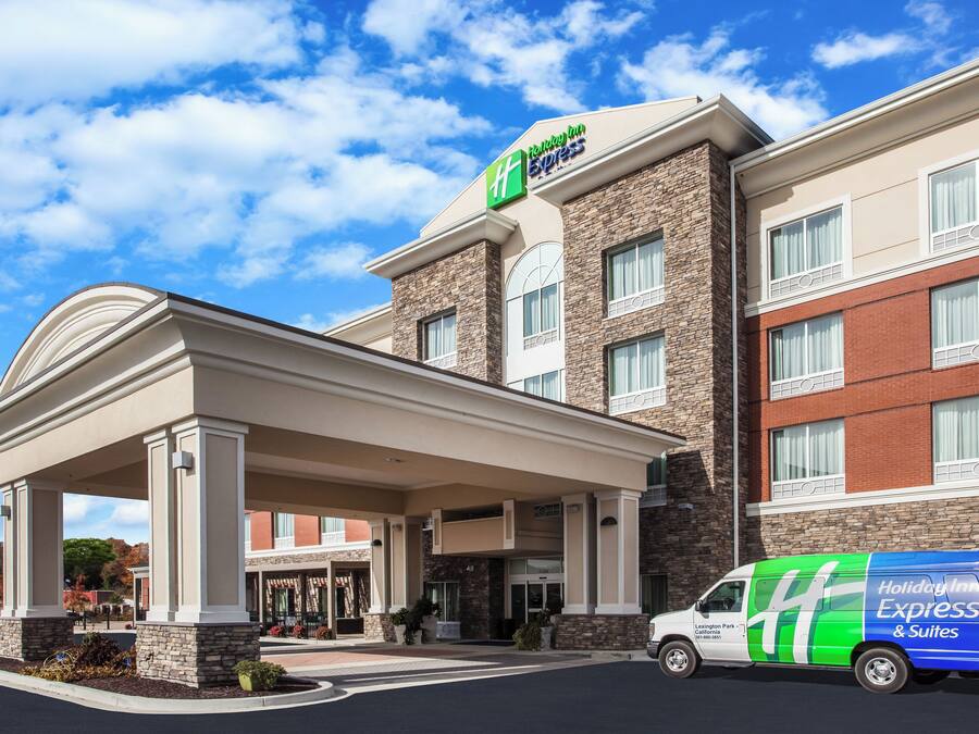 Een Holiday Inn Express gebouw met een overdekte ingang, een gevel van natuursteen en een bestelwagen ervoor geparkeerd.