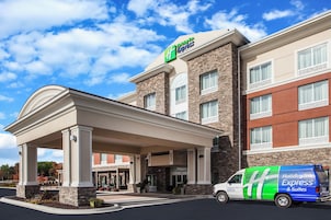 Edificio de Holiday Inn Express con entrada cubierta, fachada de piedra y una furgoneta estacionada frente.