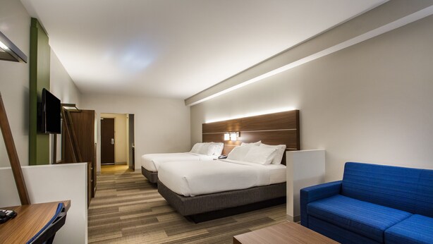 Una habitación de hotel con dos camas, un sofá azul, un escritorio y un televisor.