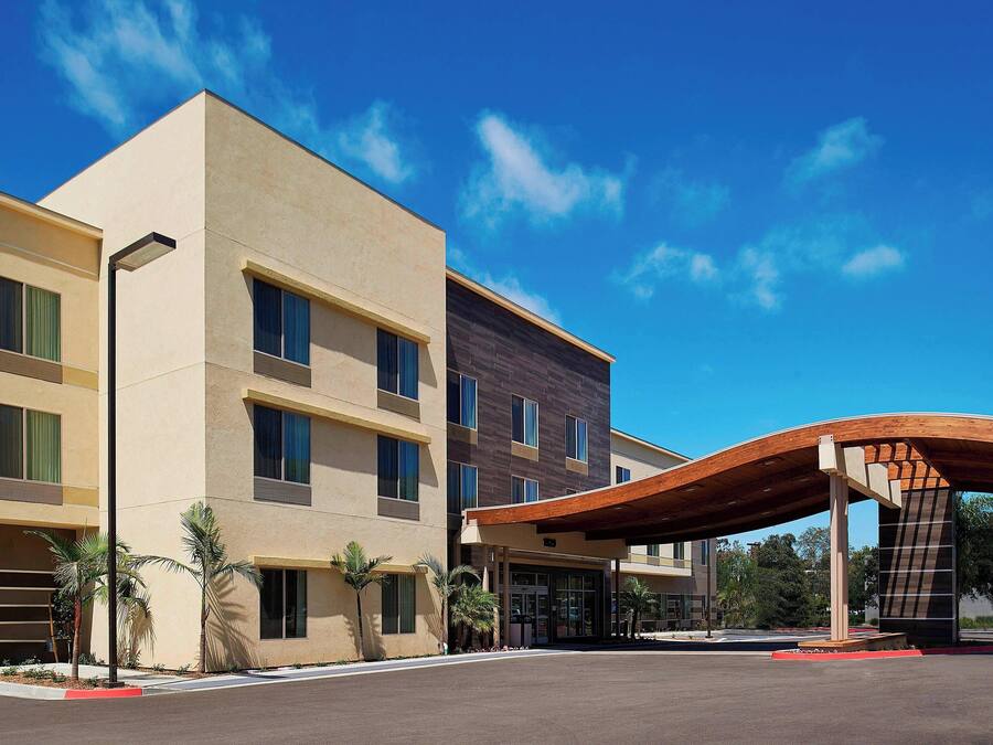 A modern hotel with a flat facade, multiple windows, and a covered entrance.