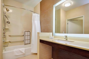 Un baño con bañera, ducha y tocador con espejo.