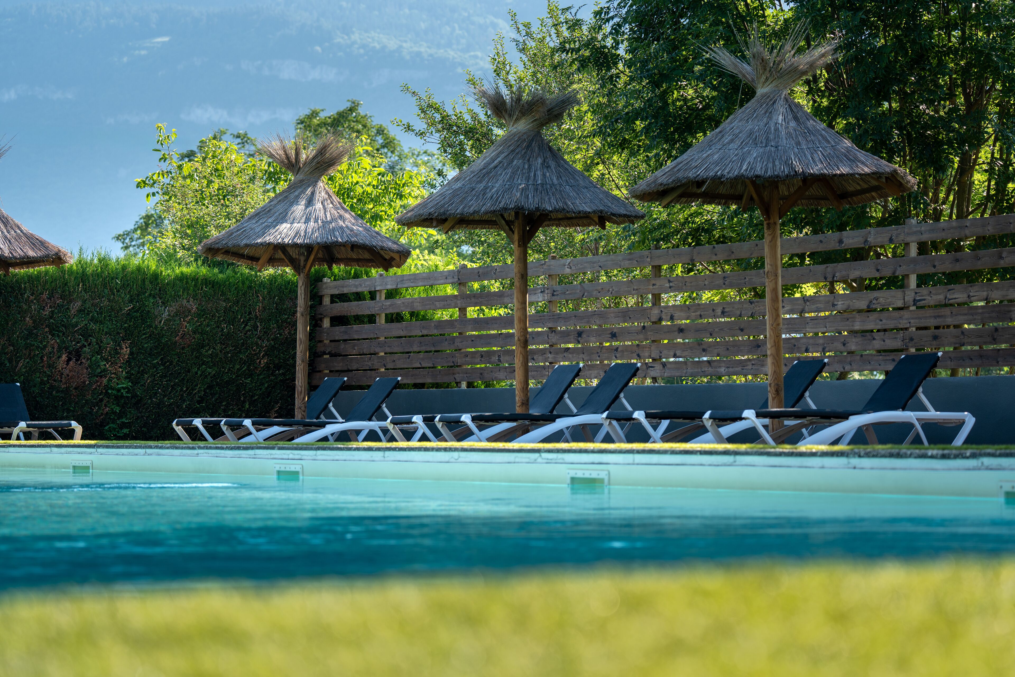 A swimming pool with lounge chairs and thatched umbrellas.