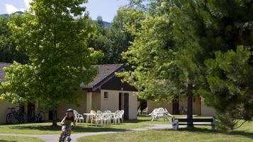 A cyclist on a path, outdoor seating, and a building with a tiled roof.