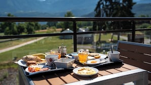 A breakfast tray with various foods and drinks on a balcony overlooking a mountainous landscape. - Hôtel le Pré du Lac (Saint-Jorioz)