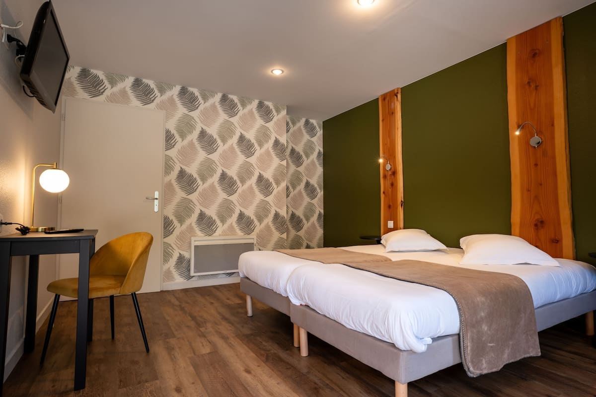 Une chambre à coucher avec un lit, un bureau, une chaise et un téléviseur fixé au mur.