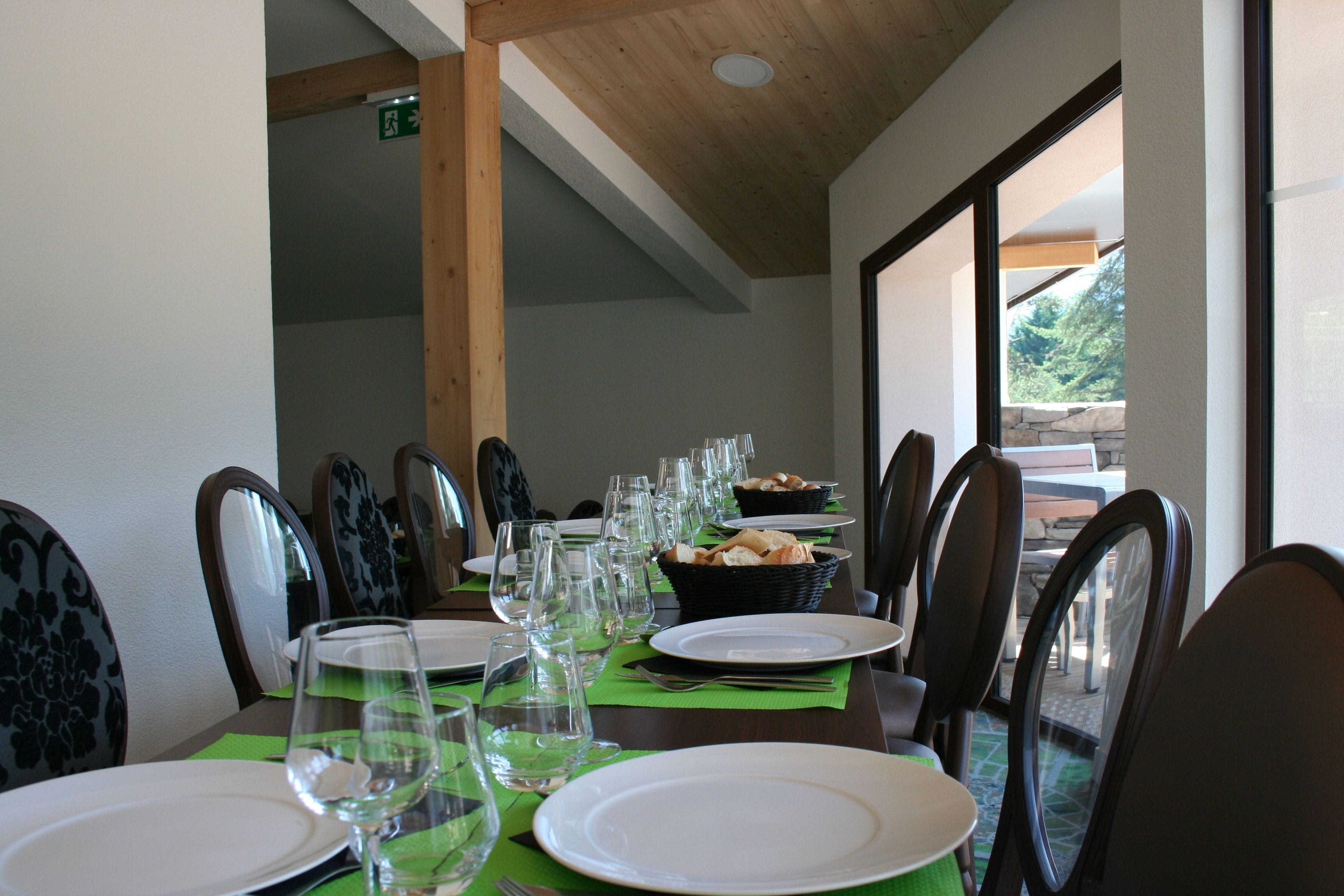 A dining area with tables set for a meal, chairs, and a view of the outdoors.