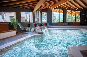 Uma área de spa com hidromassagem, assentos e amplas janelas com vista para o exterior.