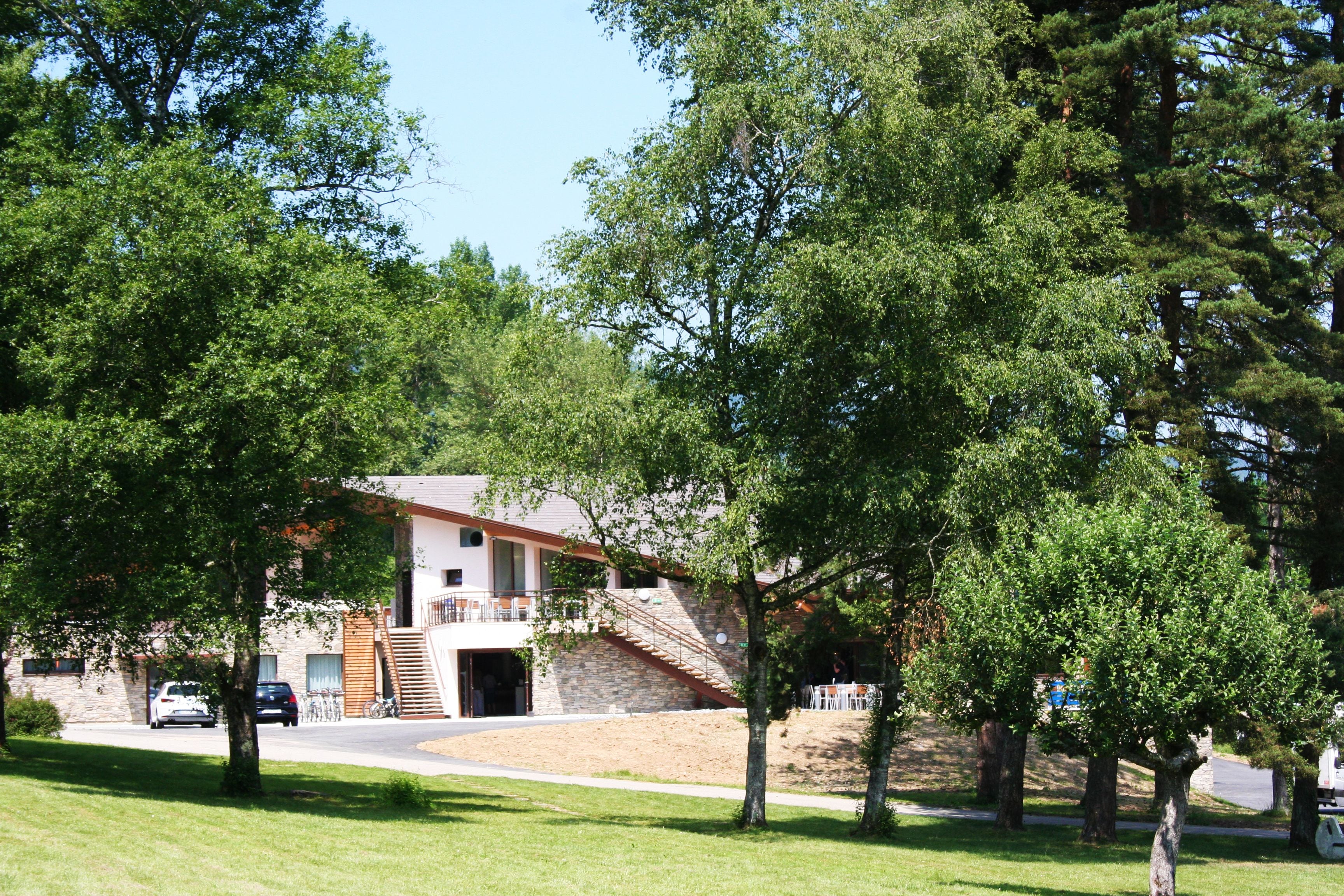 A two-story building with a stone facade, a staircase leading to the upper level, and a car parked in front.