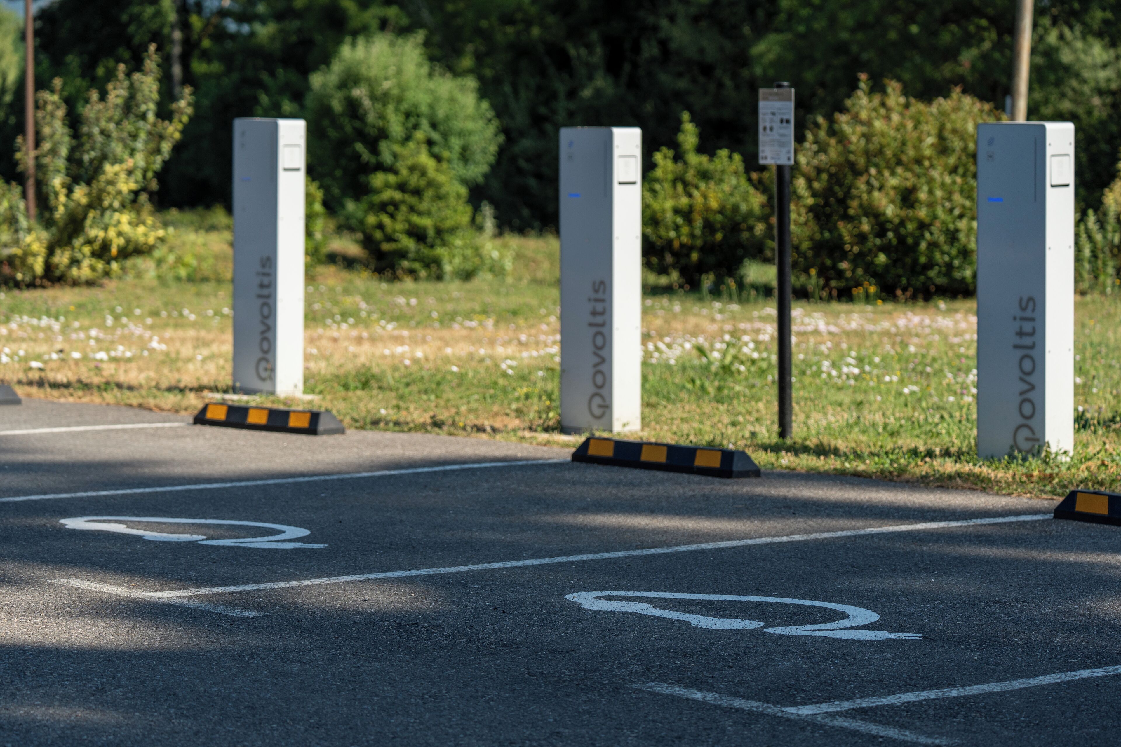 Un área de estacionamiento con bolardos con la etiqueta "Povoltis" y un carril bici.