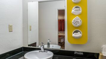 A bathroom with a white sink, a mirror, and a yellow towel rack with towels.
