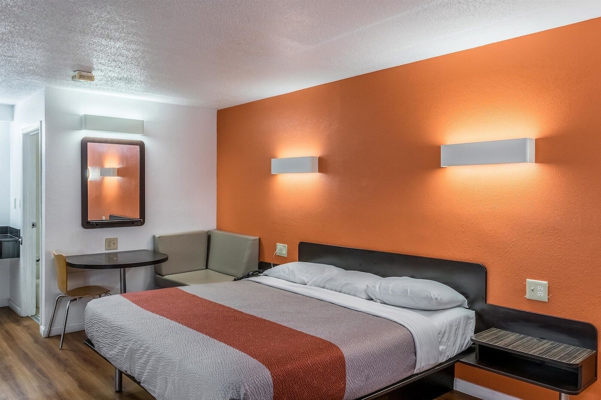 Une chambre d’hôtel avec un lit, une petite table, une chaise et une table de chevet.